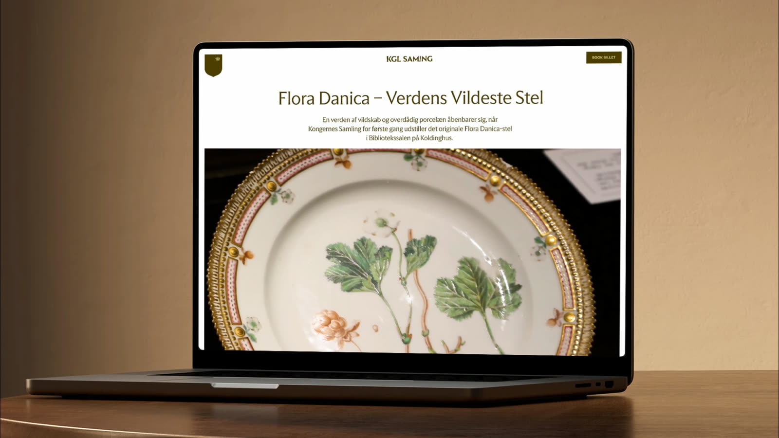A laptop on a wooden desk showing the Flora Danica exhibition page — the title “Flora Danica – Verdens Vildeste Stel” above a close-up of a hand-painted porcelain plate.